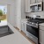 a kitchen with white cabinets a sink a stovetop and large windows