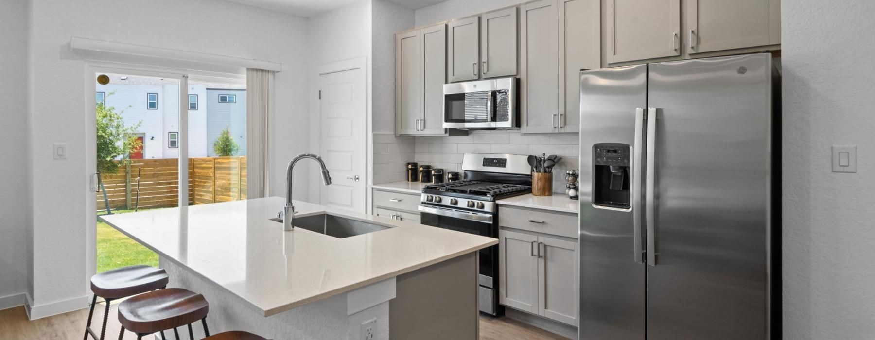 a kitchen with white cabinets a white island a fridge a sink and a stovetop