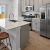 a kitchen with white cabinets a white island a fridge a sink and a stovetop